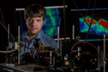 Karl Deisseroth looking at the camera over a microscope