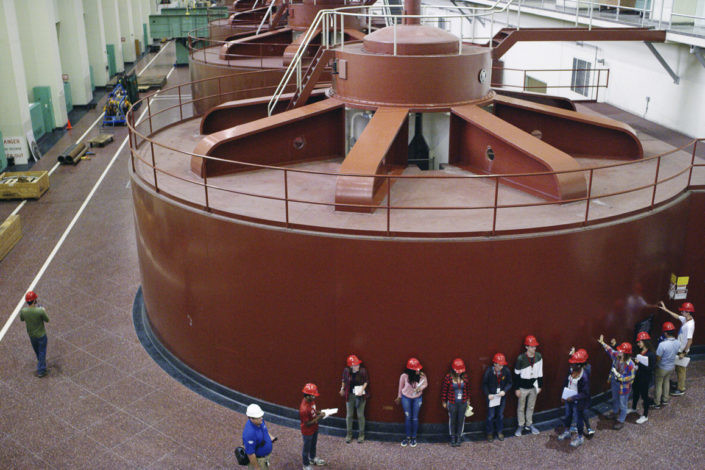 Stanford students stand next to a generator inside a dam)