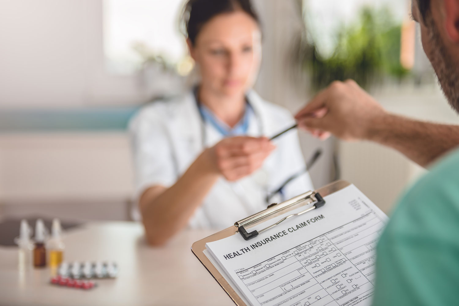 at the doctor's office, receptionist hands man a health insurance claim form