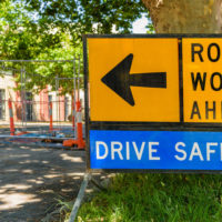 road closure sign with construction in the background