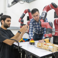 Ajay Mandelkar and Jim Fan use their software to control the robot arm using a handheld device.