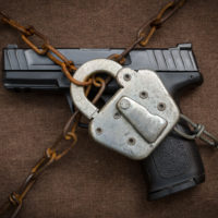 Pistol behind lock and chains symbolic of gun control