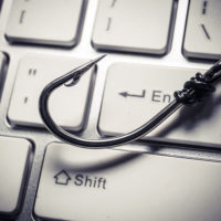 a fish hook on computer keyboard representing phishing attack on computer system