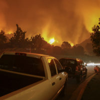 Residents of a neighborhood sit by and watch a fire threaten their homes.