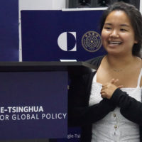 Student Yvonne Lee standing near a banner with logo of Carnegie-Tsinghua logo