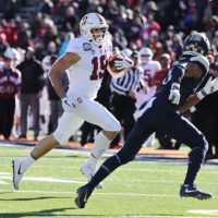 Stanford football player rinning with the ball with an opponent tries to head him off.