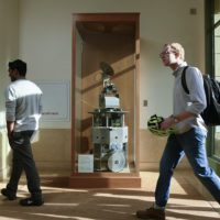 Mobi inside a display case with three people walking by