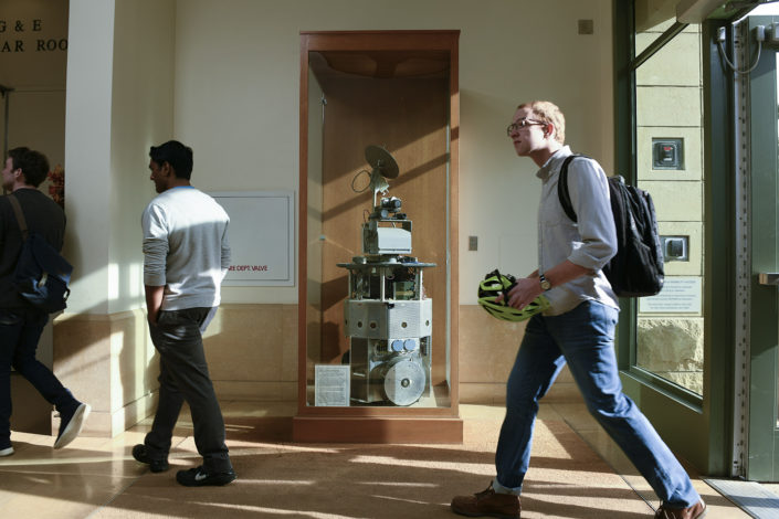 Mobi inside a display case with three people walking by