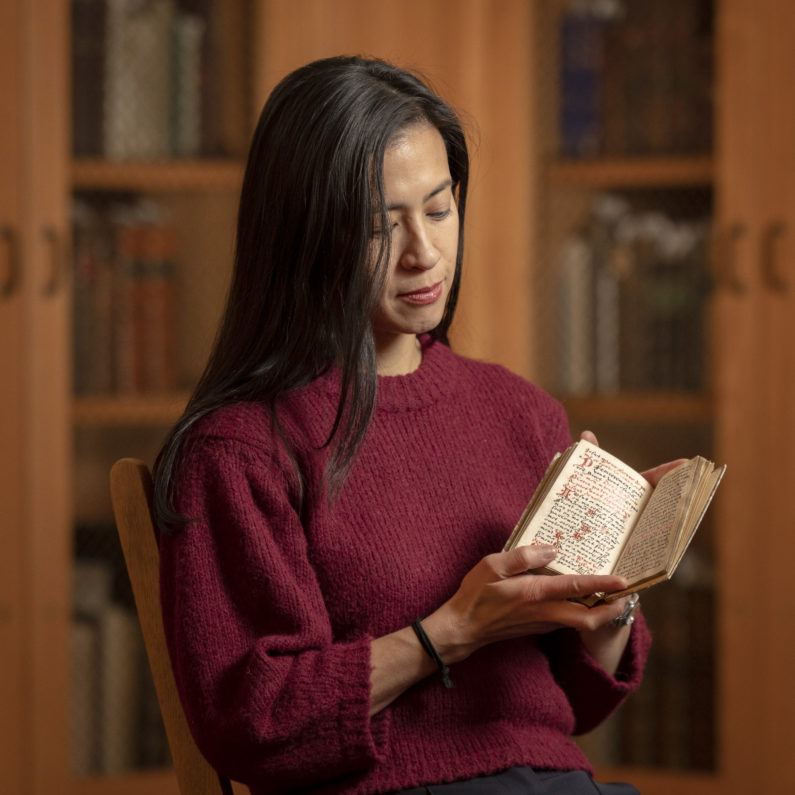 Marisa Galvez holds a contemplative manuscript from the 16th century made for a Franciscan nun