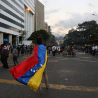 protestor wearing Venezuelan flag as a cape