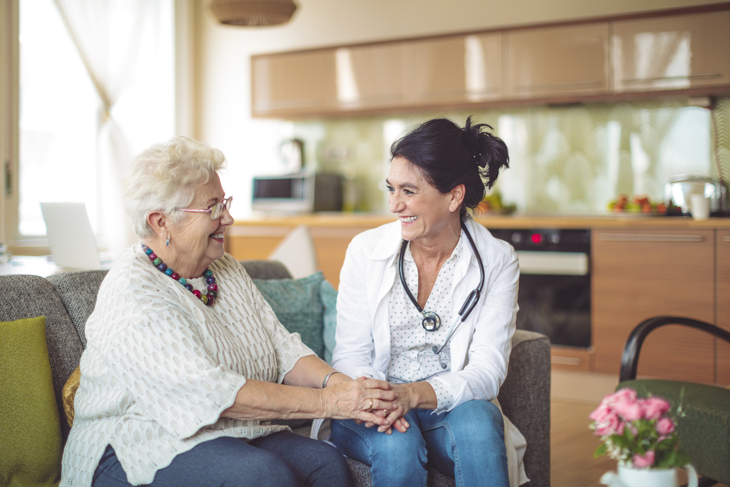 Doctor is sitting with a senior woman in a kitchen