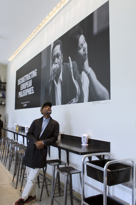 Artist Kahlil Joseph pauses in front of a BLKNWS poster in the Cantor Café.