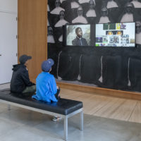 Visitors at Stanford’s Cantor Arts Center absorb the video images from Kahlil Joseph’s BLKNWS, 2018.