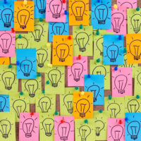 bulletin board covered with sticky notes embellished with drawings of lightbulbs representing ideas