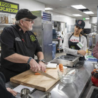 Iott and students stand at a kitchen table.