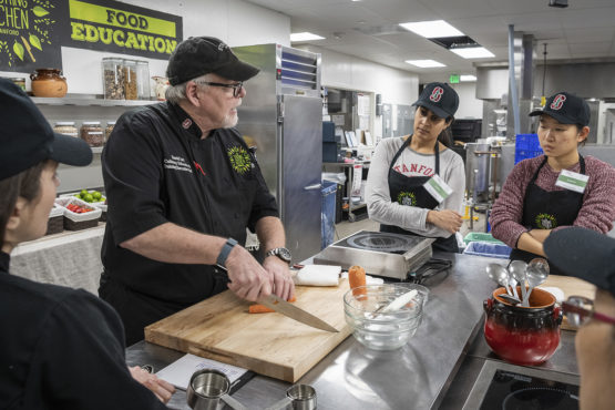 Iott and students stand at a kitchen table.