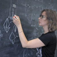 Physicist Natalie Paquette working at a chalkboard