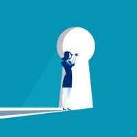 Businesswoman peers through a large keyhole.