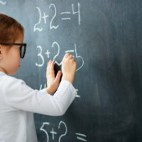 Schoolgirl writing figures on blackboard