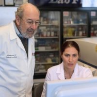 two people in lab coats looking at computer