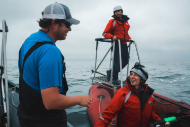 A person on one boat talks with two people on another boat