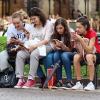 girls on a bench looking at their phones