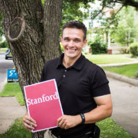 Jason Spyres holding a folder with Stanford logo on the cover