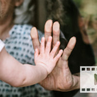 toddler and elder touching through glass