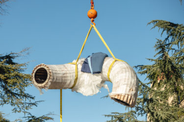 A crane lifts one of the five sections of the sculpture into place