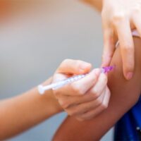 Child receives vaccination in arm.