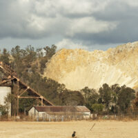 Landscape of old disused mineshaft, showing a mine dump behind, and heavy rain clouds, in Boksburg South Africa